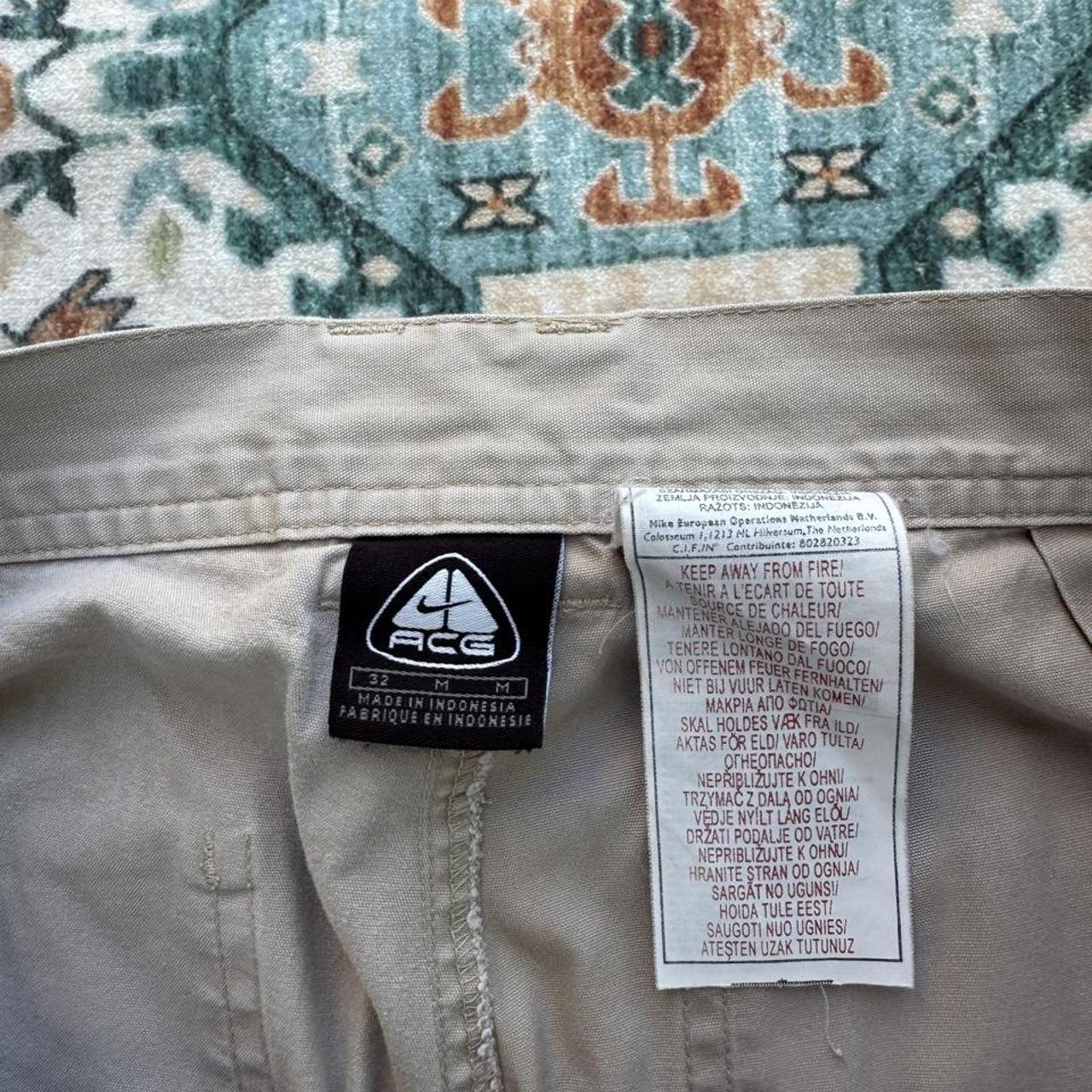 Nike ACG beige cargo pants with embroidered logo and multiple pockets.