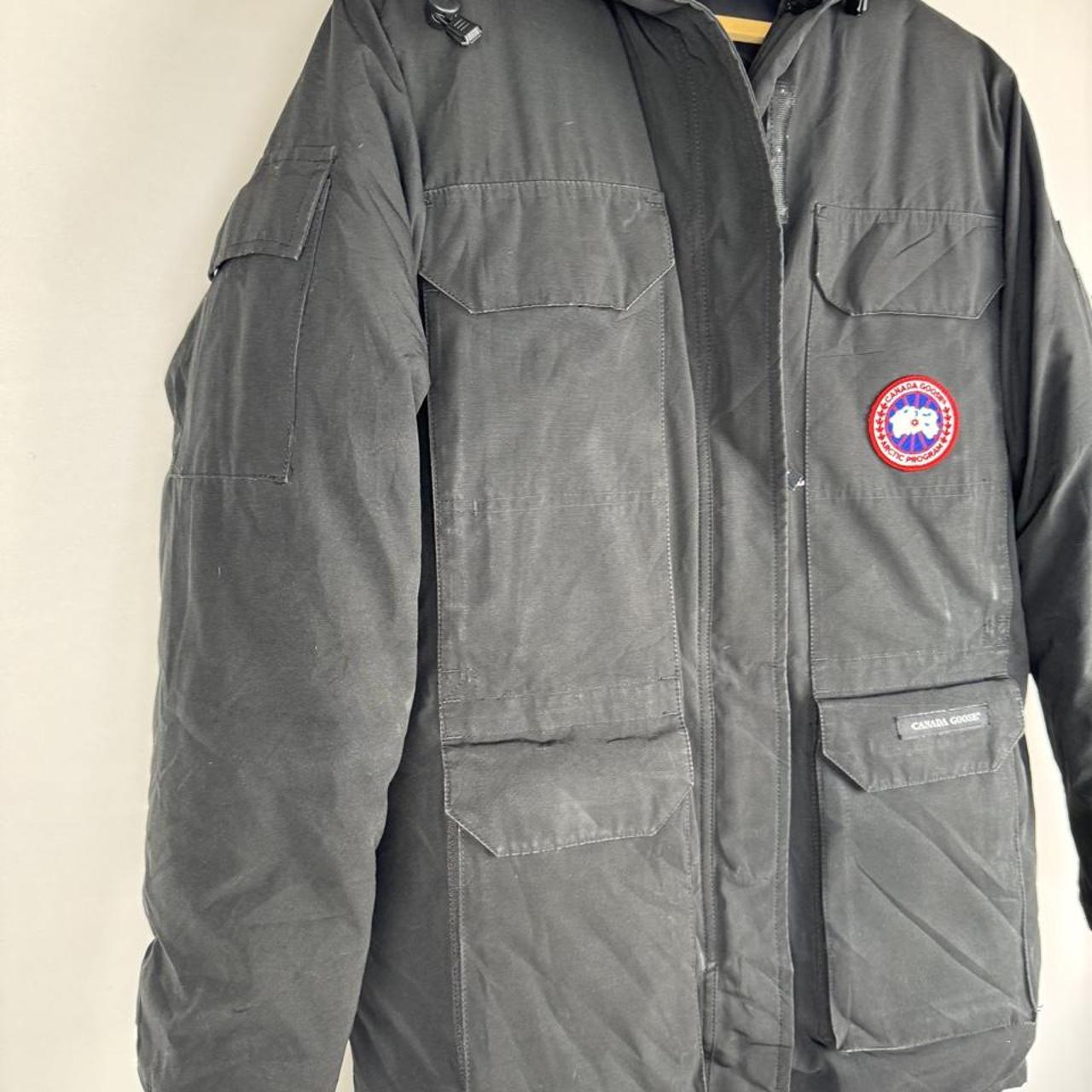 Canada Goose black parka jacket with logo patch and fur-lined hood.