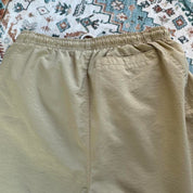 Nike ACG cream swim shorts with logo detail and lightweight material.