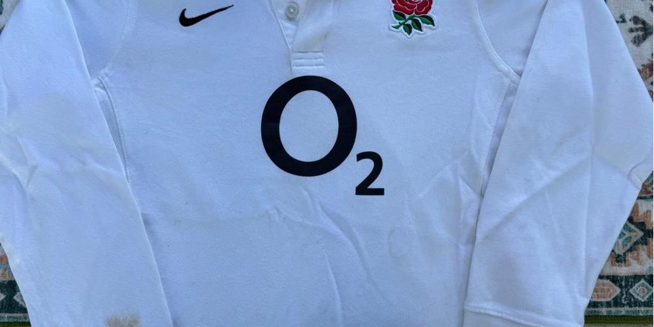 Nike black and white rugby polo shirt with England logo and striped pattern.