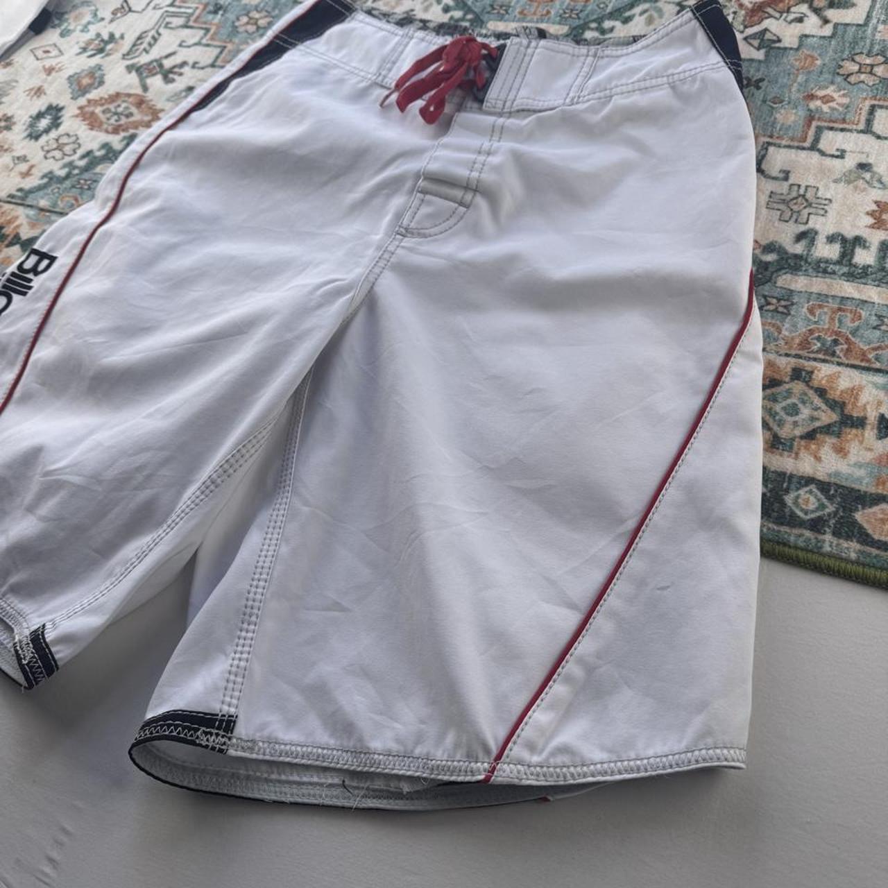 Billabong board shorts blue with embroidered Taj Burrow signature and tropical pattern.