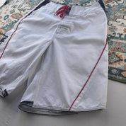 Billabong board shorts blue with embroidered Taj Burrow signature and tropical pattern.