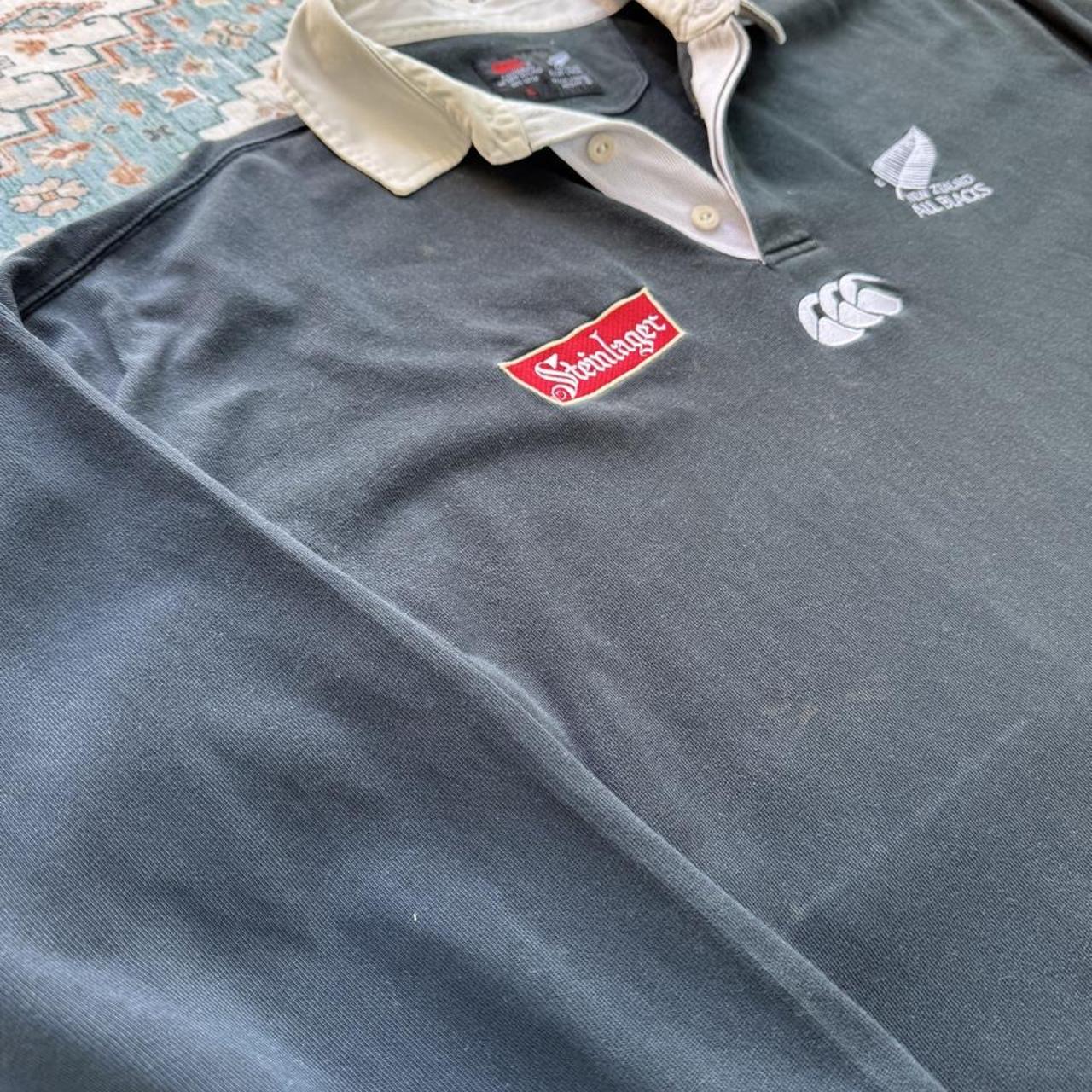 Canterbury men's polo shirt black with All Blacks logo and rugby pattern details.