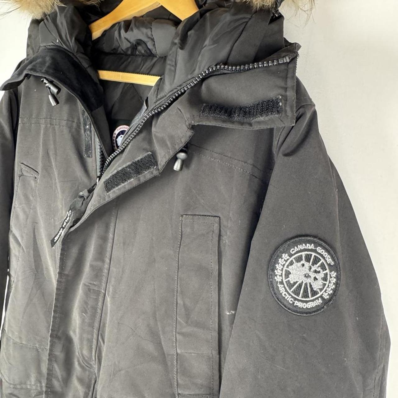 Canada Goose black parka jacket with logo patch and fur-trimmed hood.