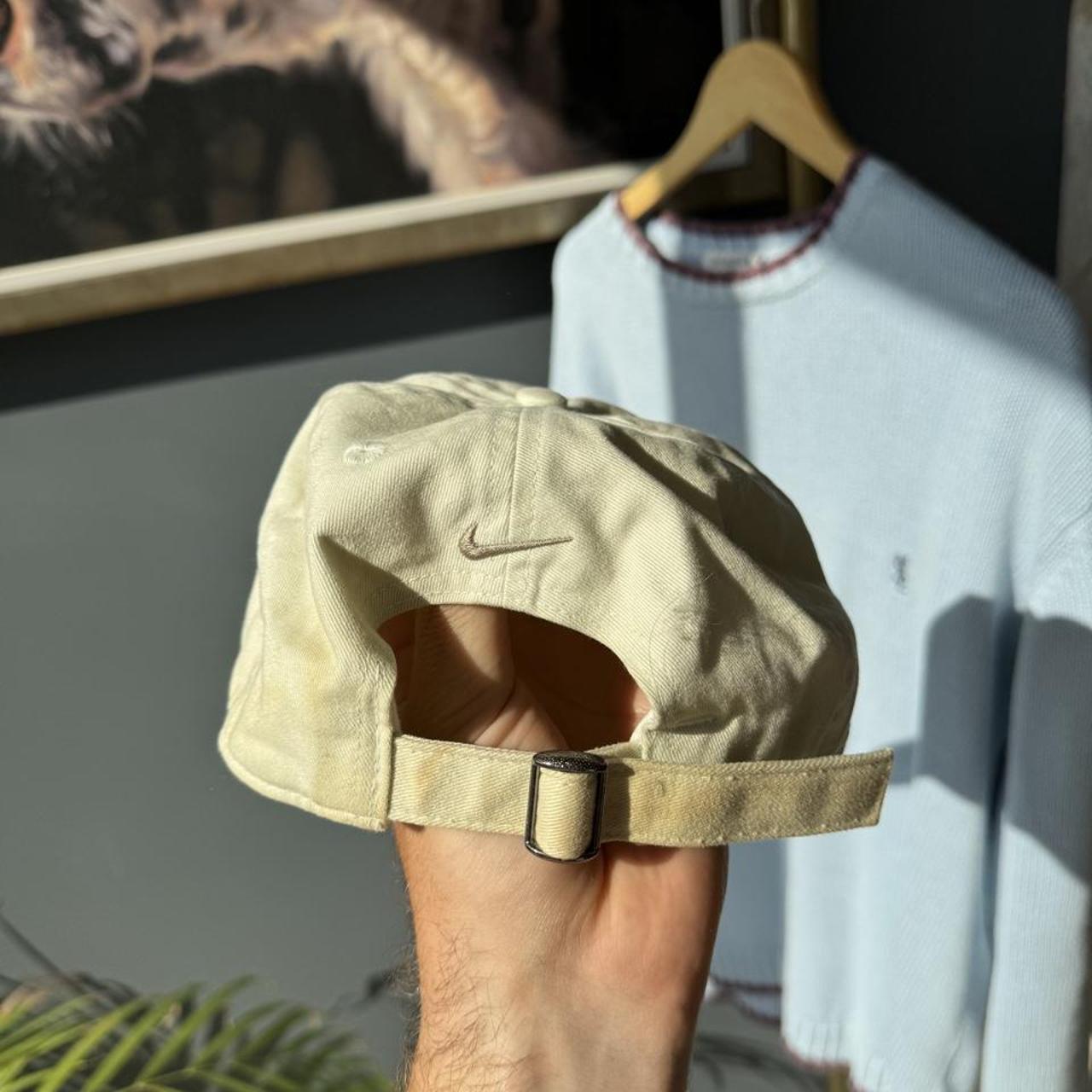 Nike cream cap with embroidered logo and adjustable strap.