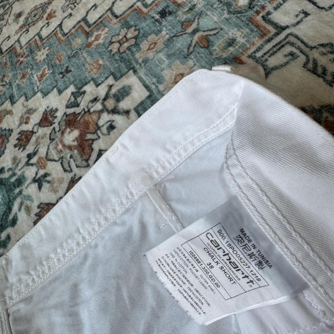 Carhartt WIP white shorts with slight yellowing, featuring classic logo and durable fabric.