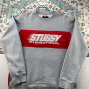 Stüssy grey sweatshirt featuring international logo and soft cotton material.