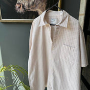 Yves Saint Laurent cream short sleeve shirt with embroidered YSL logo and button details.