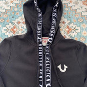 True Religion black and white full zip hoodie with logo and contrast stitching.