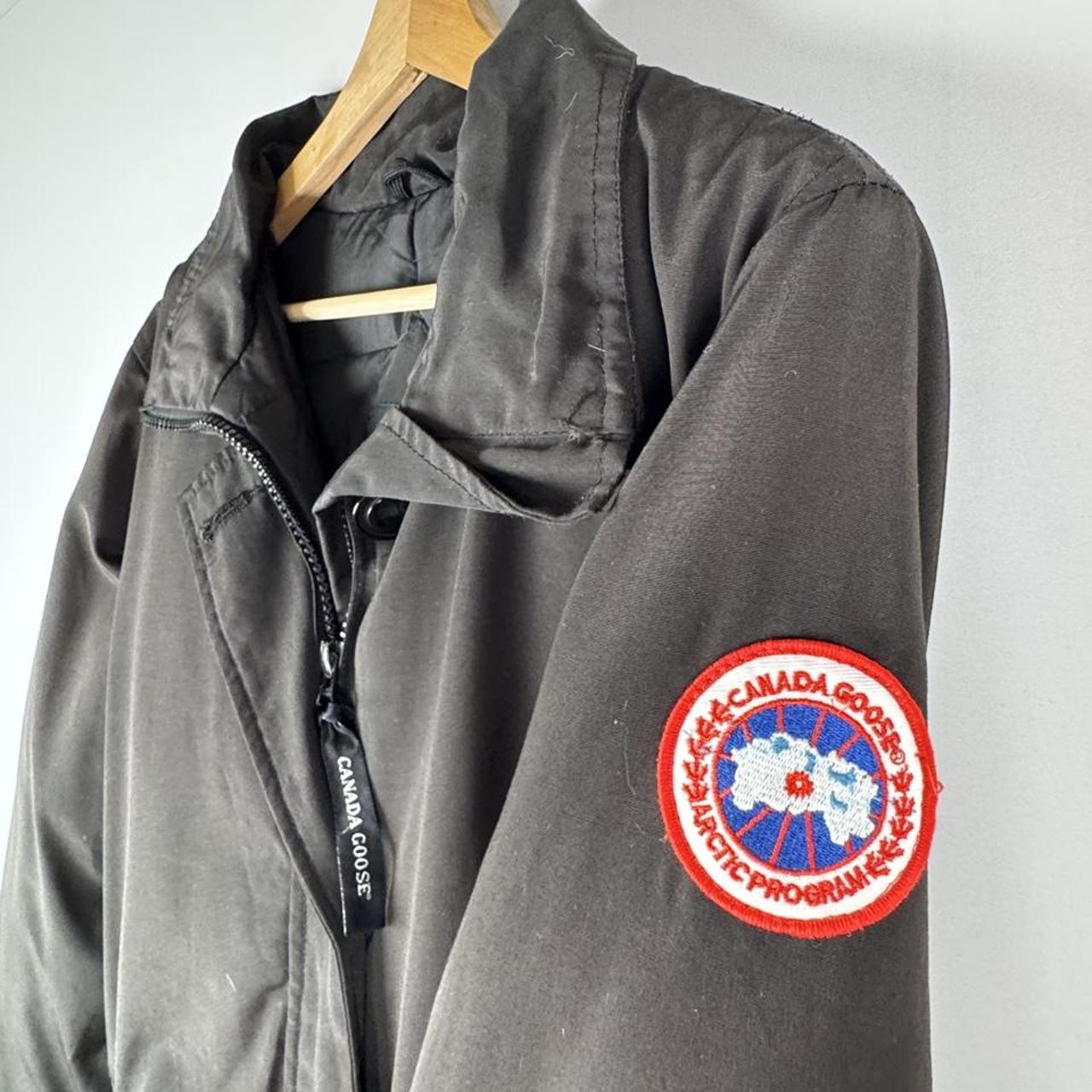 Canada Goose black parka jacket with logo, slight tear near pocket, missing hood.