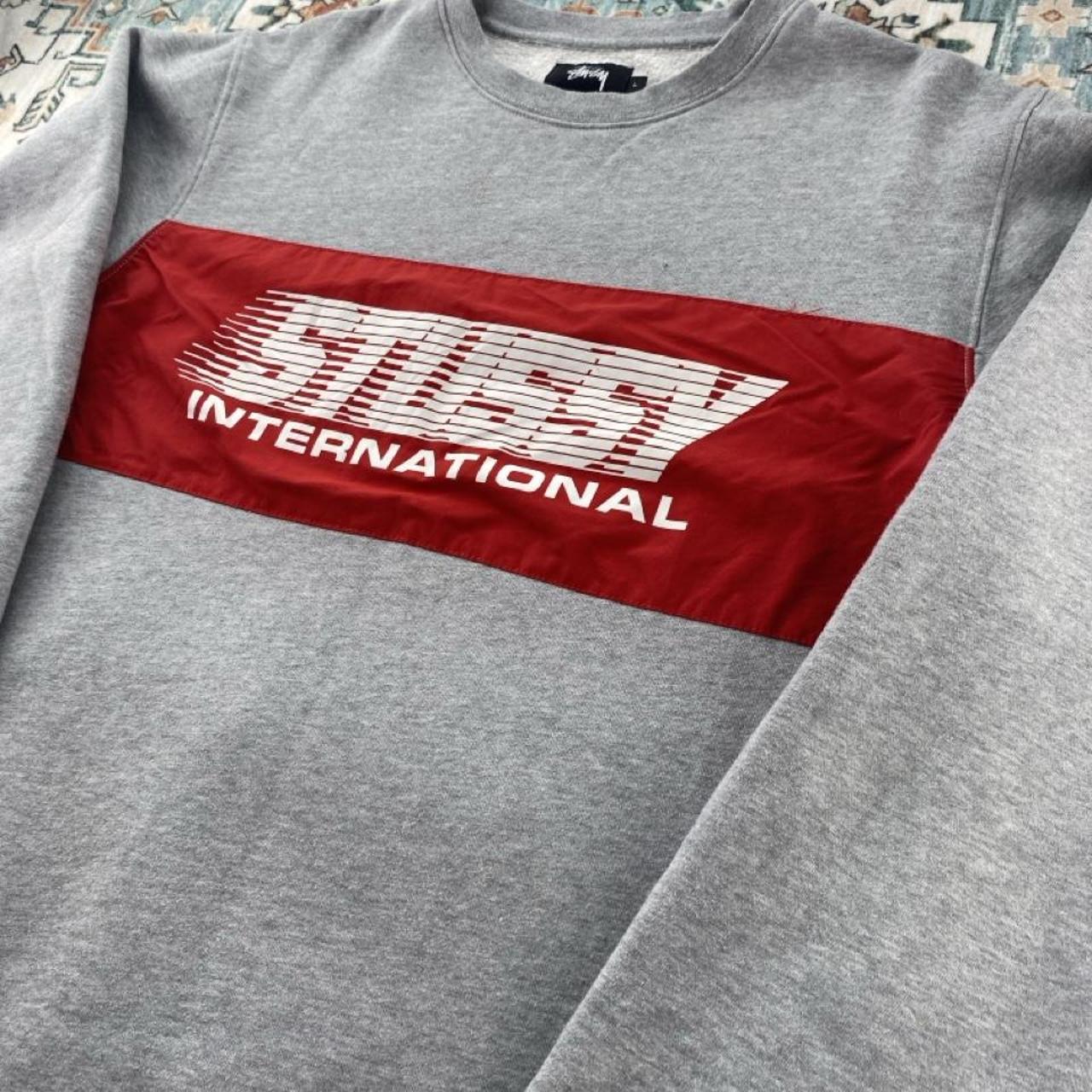 Stüssy grey sweatshirt featuring international logo and soft cotton material.