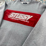 Stüssy grey sweatshirt featuring international logo and soft cotton material.
