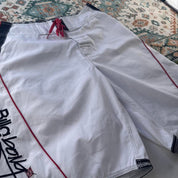 Billabong board shorts blue with embroidered Taj Burrow signature and tropical pattern.
