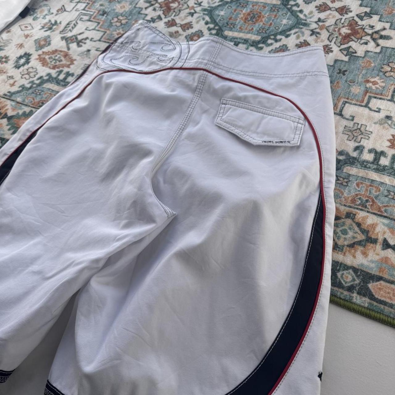 Billabong board shorts blue with embroidered Taj Burrow signature and tropical pattern.