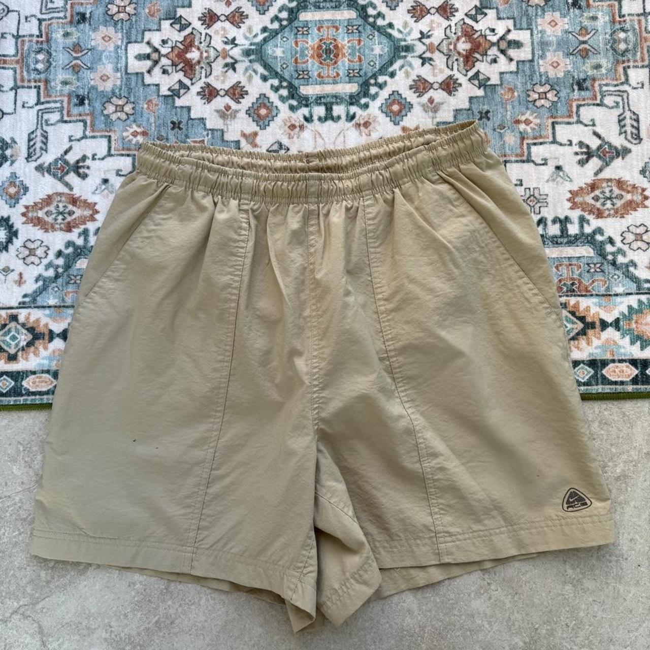 Nike ACG cream swim shorts with logo detail and lightweight material.