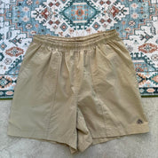 Nike ACG cream swim shorts with logo detail and lightweight material.