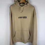 Stüssy oversized beige hoodie with Tribe spellout logo and relaxed fit.