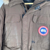 Canada Goose brown parka jacket with logo patch and utility pockets.