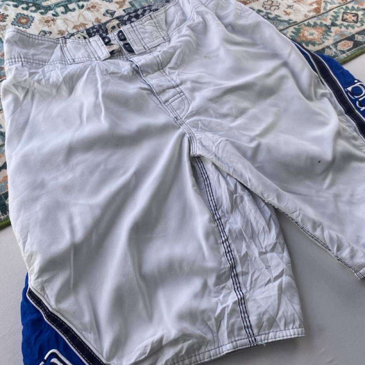 Billabong board shorts blue with tropical print and Andy Irons logo detail.