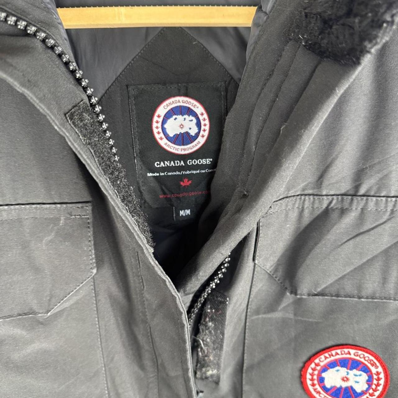 Canada Goose black parka jacket with logo patch and fur-lined hood.