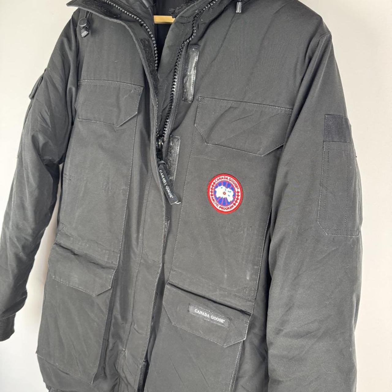 Canada Goose black parka jacket with logo patch and fur-lined hood.