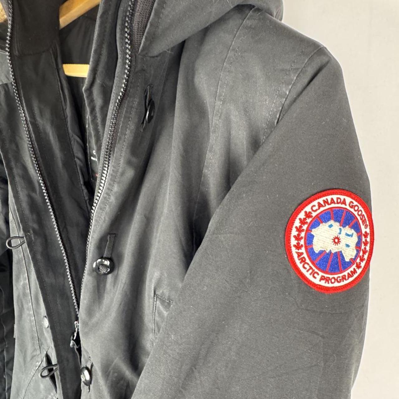 Canada Goose black parka jacket with logo patch and fur-lined hood.