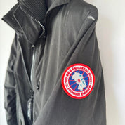 Canada Goose black parka jacket, medium size, features logo patch and sleek design.