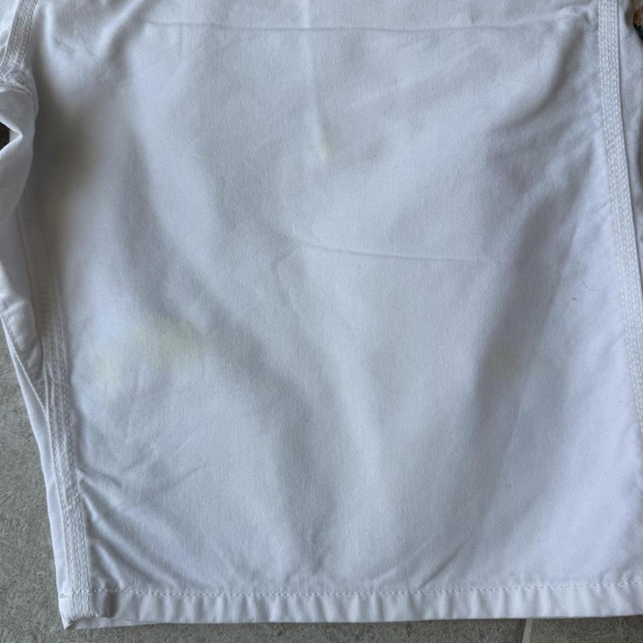 Carhartt WIP white shorts with slight yellowing, featuring classic logo and durable fabric.