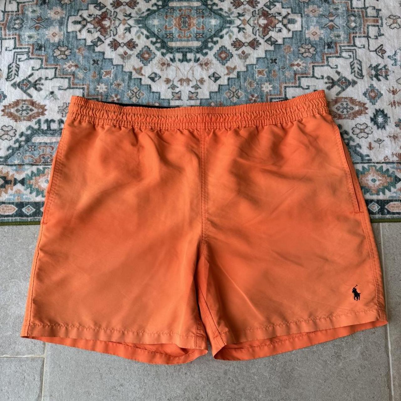 Polo Ralph Lauren orange swim trunks with iconic embroidered logo and lightweight fabric.