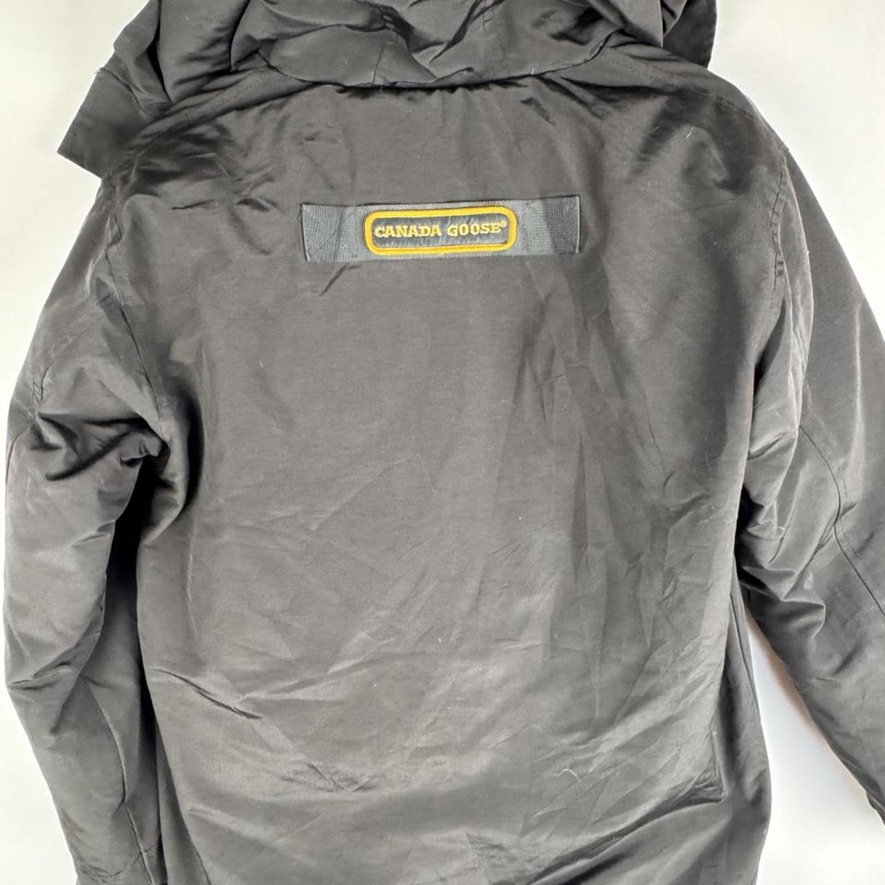 Canada Goose black parka jacket with logo patch and fur-trimmed hood.