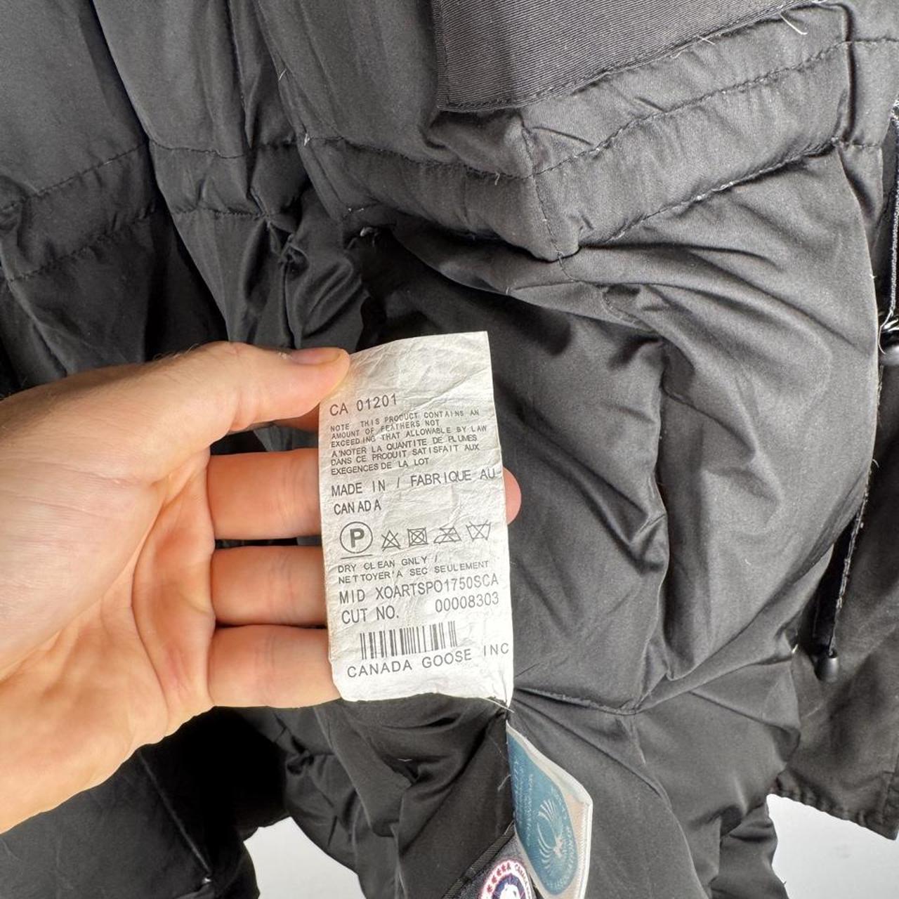 Canada Goose black parka jacket with logo, slight tear near pocket, missing hood.