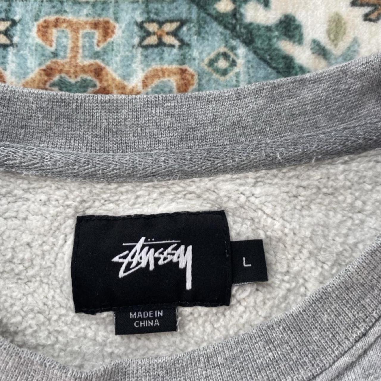 Stüssy grey sweatshirt featuring international logo and soft cotton material.