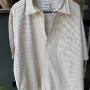 Yves Saint Laurent cream short sleeve shirt with embroidered YSL logo and button details.