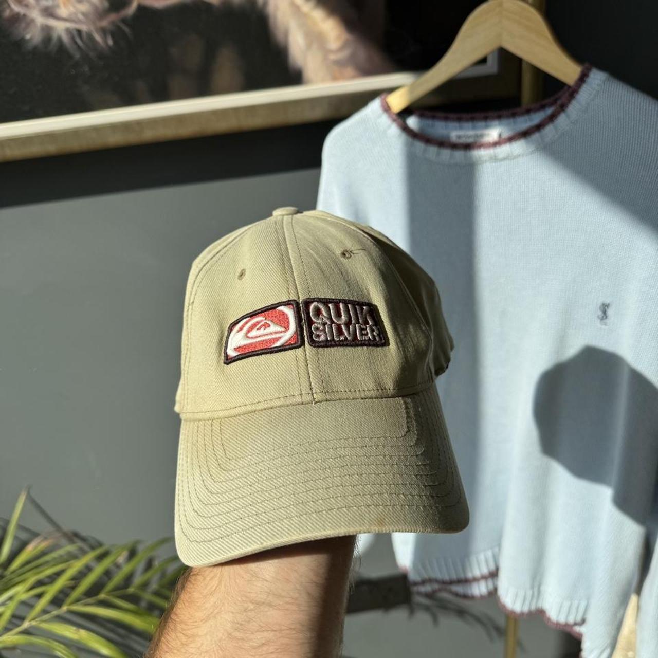 Quiksilver cream cap with embroidered surf logo and adjustable strap.