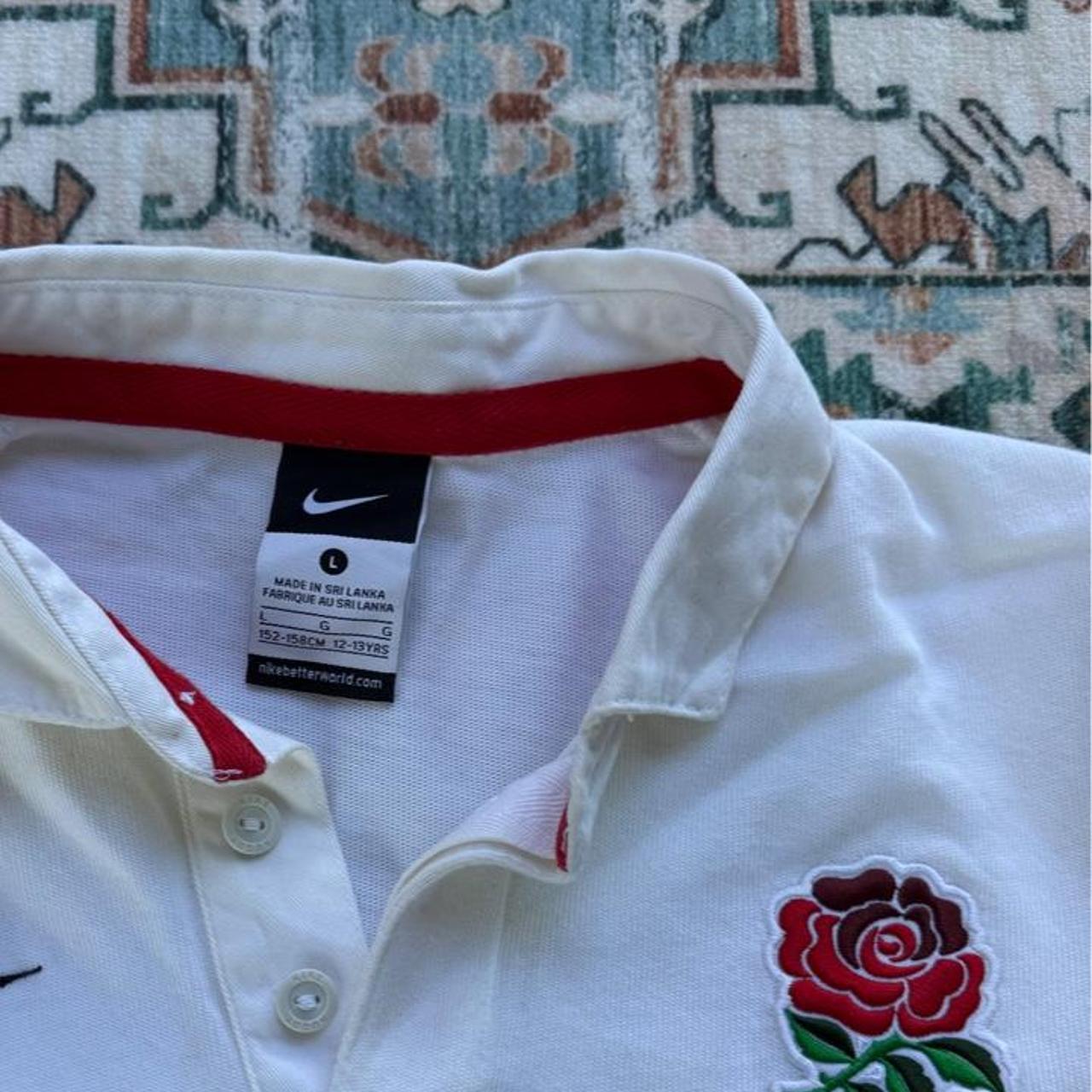 Nike black and white rugby polo shirt with England logo and striped pattern.
