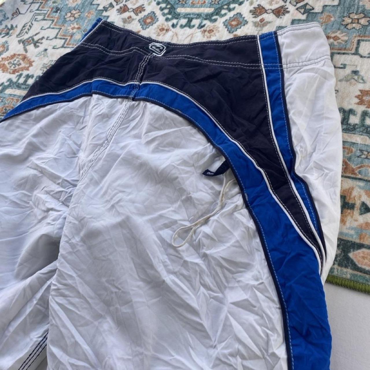 Billabong board shorts blue with tropical print and Andy Irons logo detail.