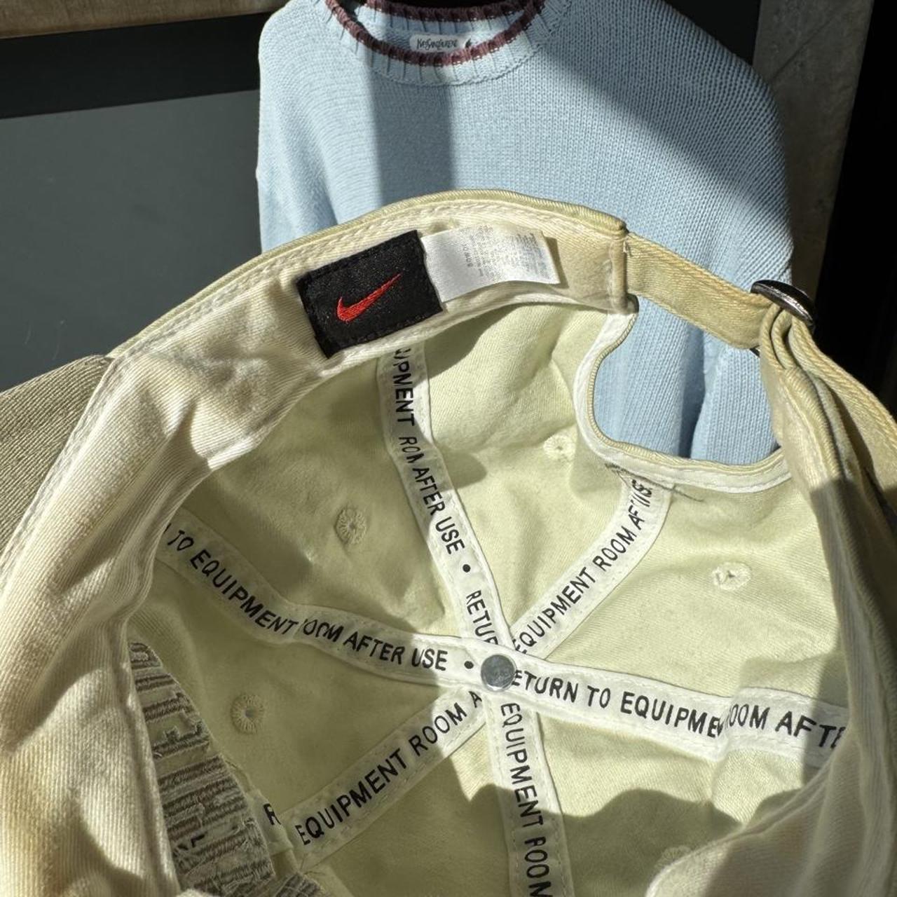 Nike cream cap with embroidered logo and adjustable strap.