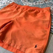 Polo Ralph Lauren orange swim trunks with iconic embroidered logo and lightweight fabric.