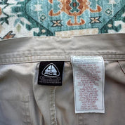 Nike ACG beige cargo pants with embroidered logo and multiple pockets.