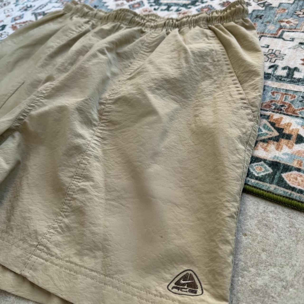 Nike ACG cream swim shorts with logo detail and lightweight material.