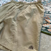 Nike ACG cream swim shorts with logo detail and lightweight material.
