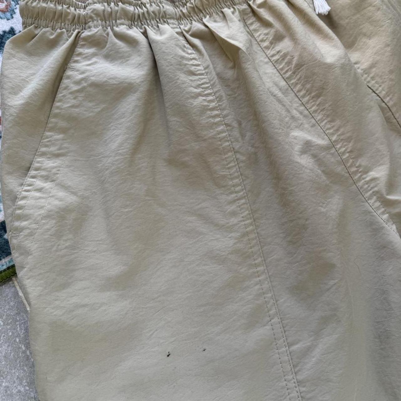 Nike ACG cream swim shorts with logo detail and lightweight material.