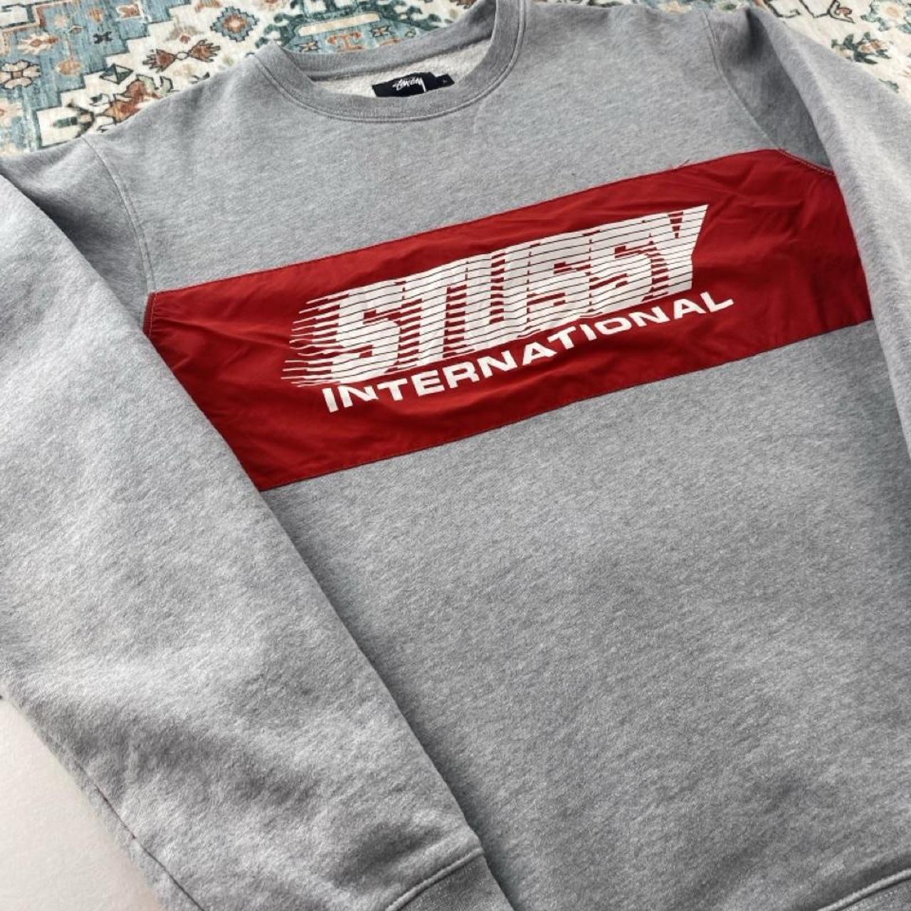 Stüssy grey sweatshirt featuring international logo and soft cotton material.