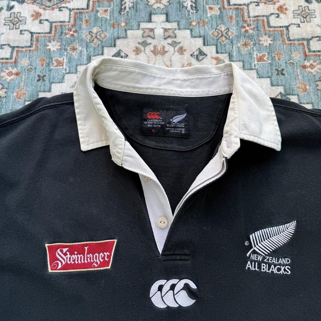 Canterbury men's polo shirt black with All Blacks logo and rugby pattern details.