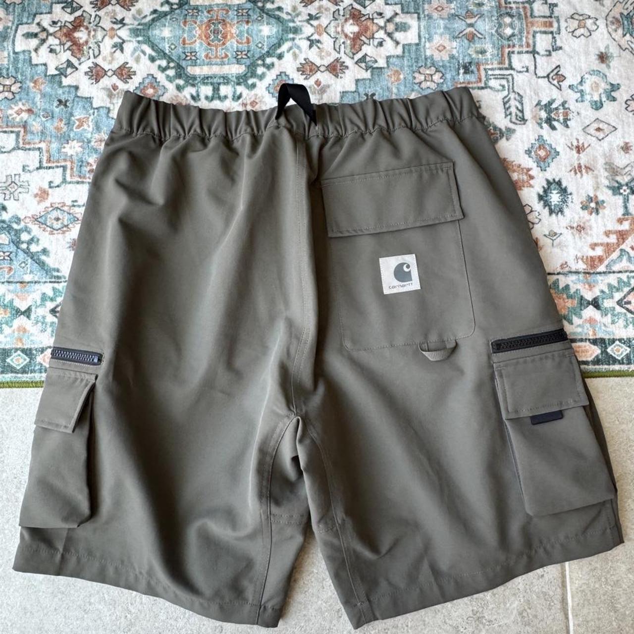 Carhartt WIP olive green cargo shorts with multiple pockets and logo patch.