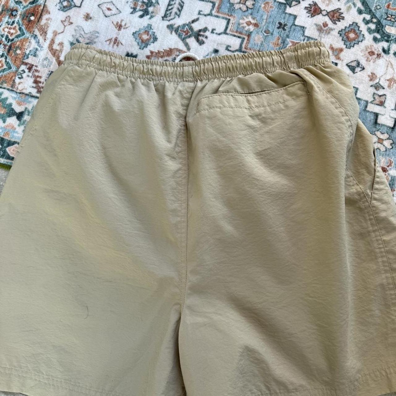 Nike ACG cream swim shorts with logo detail and lightweight material.