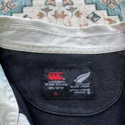 Canterbury men's polo shirt black with All Blacks logo and rugby pattern details.