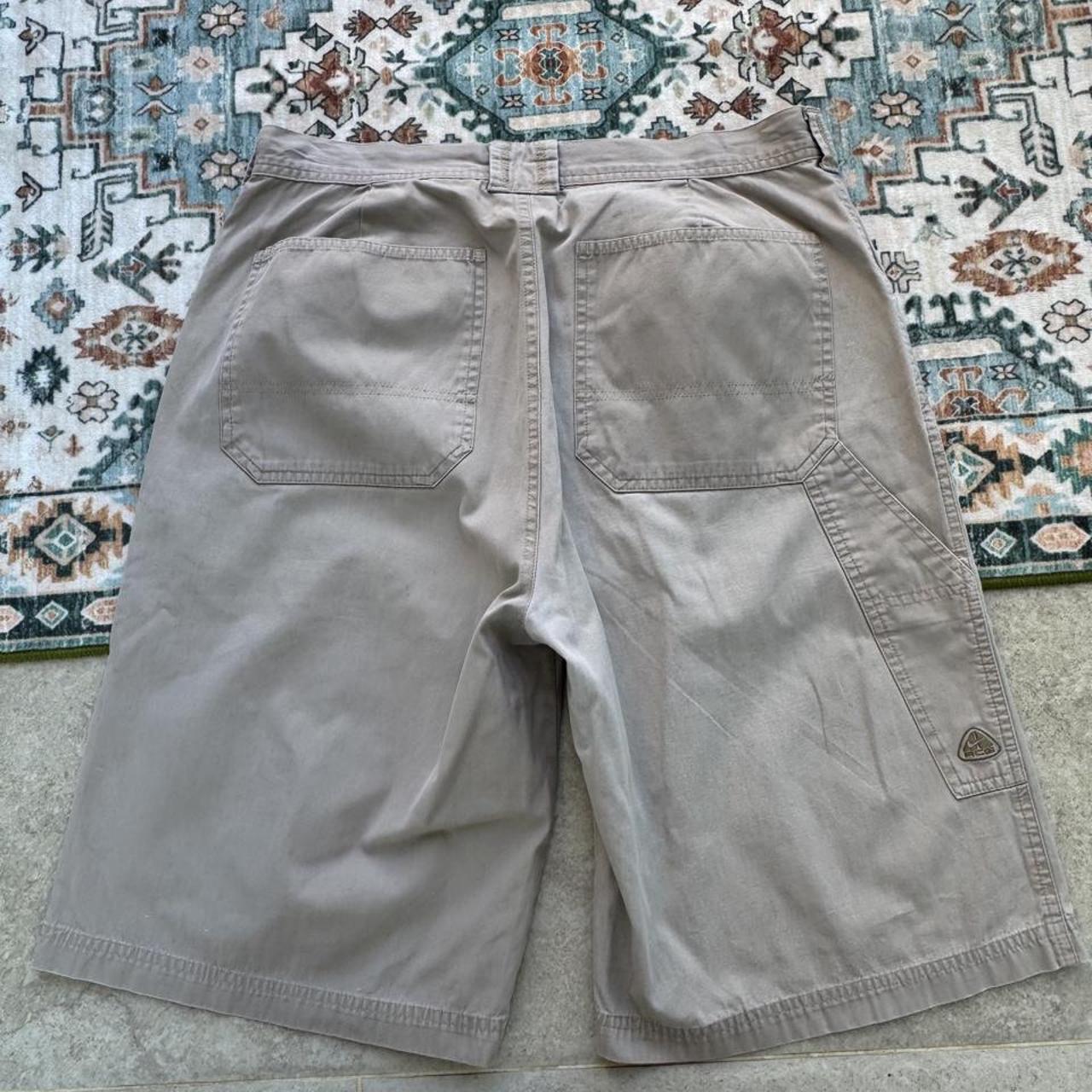 Nike ACG beige cargo pants with embroidered logo and multiple pockets.