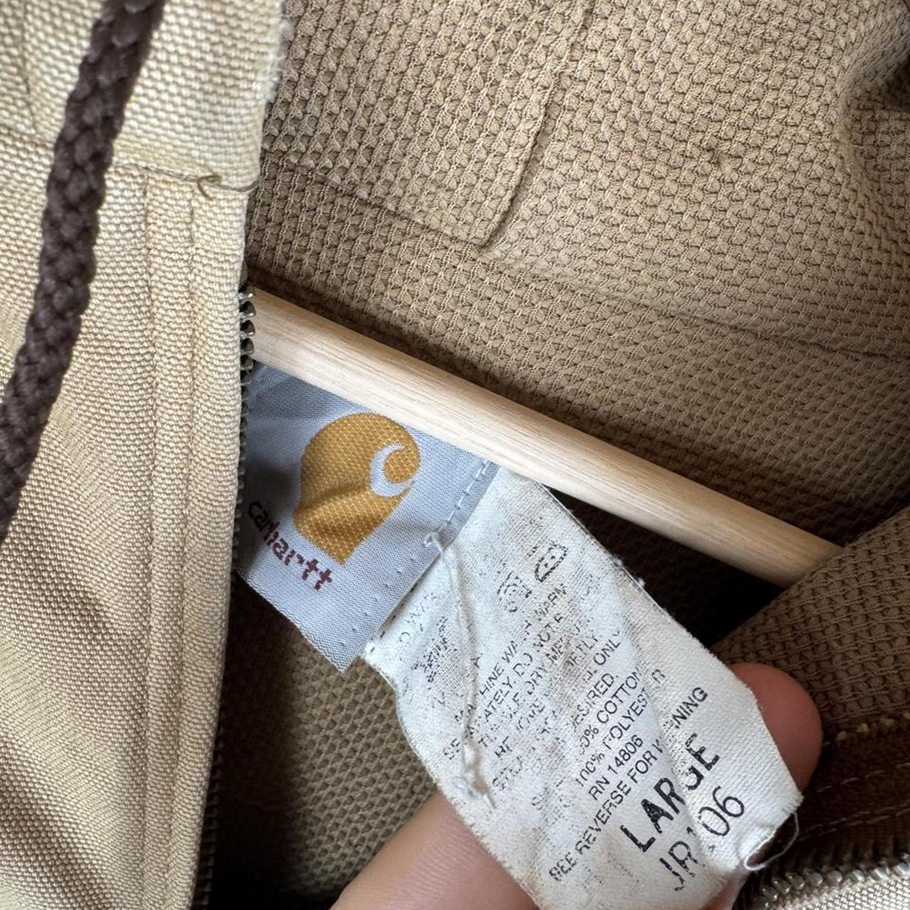 Carhartt cream distressed active jacket with logo patch and relaxed fit.