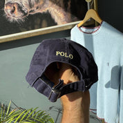 Polo Ralph Lauren navy cap with yellow embroidered logo and adjustable strap.
